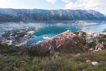 Obraz premium Kotor, Montenegro, beautiful top panoramic view of Kotor city old medieval town seen from San Giovanni St. John Fortress, with Adriatic sea, bay of Kotor and Dinaric Alps mountains in a sunny day