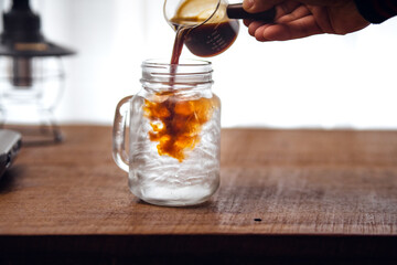 Iced coffee is pouring into the glass.
