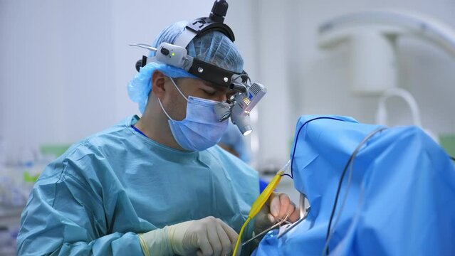 Male nasal surgeon uses electric devices in the surgery. Professional medic applies metal forceps in his work.