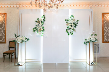 A bright photo zone in the restaurant decorated with delicate white flowers with greenery.