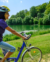 Naturgenuß bei einer Radtour im Frühsommer - Seniorin unterwegs an einem See