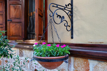 Blooming flowers in a flower pot hanging from the wall near the window in the historical part of Antalya known as Kaleiсi. Turkey.