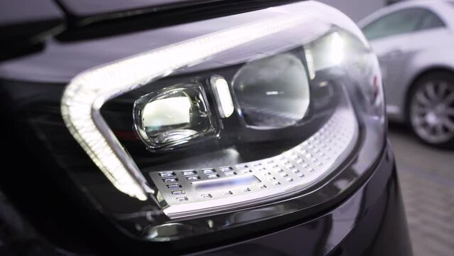 The new automatic headlight of the premium car. The included car LED headlight. The front of a new black car.