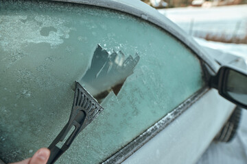 Clearing the snow from the car, after a heavy storm. Mechanical deicer tool.