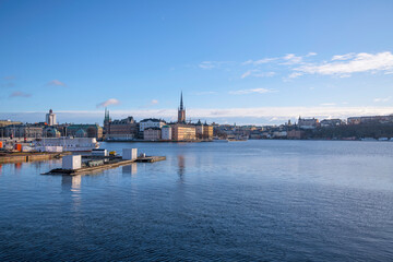 View over the bay Riddarfjärden, the old town Gamla Stan and the island Riddarholmen, commuting steam boats at the Town City Hall pier a winter day in Stockholm