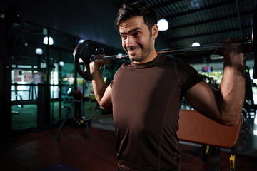 young athletic man exercising with barbell in the gym