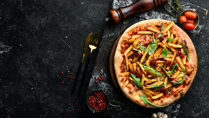 Pizza with french fries and ketchup. Home delivery of food. On a black stone background.