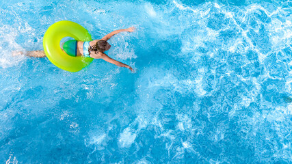 Active young girl in swimming pool aerial top view from above, teenager relaxes and swims on...