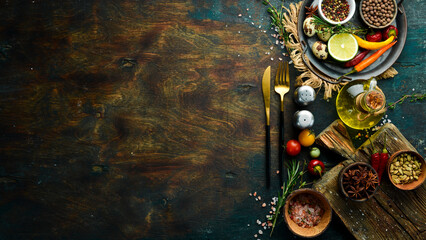 Cutlery on a black stone table with vegetables and spices. Food background. Top view. Rustic style.