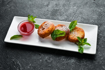 Dessert. Cheese pancakes with raspberry sauce and powdered sugar. On a black stone background.
