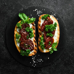Sandwich with sun-dried tomatoes, cheese and basil. Bruschetta. Top view. On a stone background.