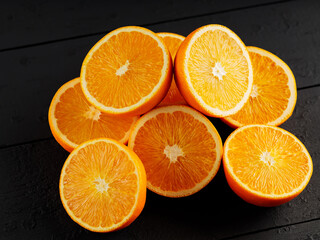 Bright halves of oranges on a wooden table. Halves of juicy oranges on black boards