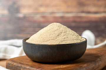 Powdered white pepper spice. Ground powdered white peppercorns in a bowl on a wooden background. Dry spice concept. close up