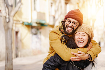 Two couple Friends Piggyback laughing together. Asian woman and hispanic man having fun in winter 