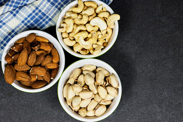 nuts (almonds, pistachio, cashews) in bowls on grunge background
