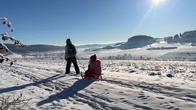 Footage of a happy family riding a sledge in a beautiful winter landscape