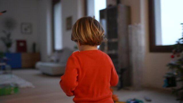 One excited happy child running in modern living room home. Back of small kid runner in house interior. Handheld footage in slow motion