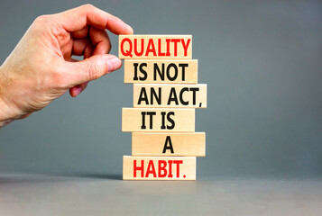 Quality is a habit symbol. Concept words Quality is not an act it is a habit on wooden blocks. Beautiful grey table grey background. Businessman hand. Business quality is habit concept. Copy space.