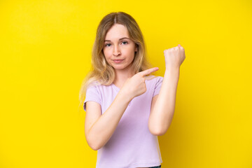 Blonde English young girl isolated on yellow background making the gesture of being late