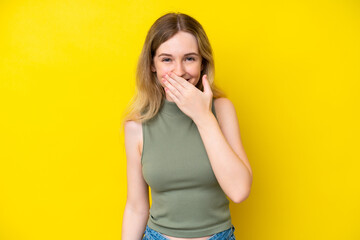 Blonde English young girl isolated on yellow background happy and smiling covering mouth with hand