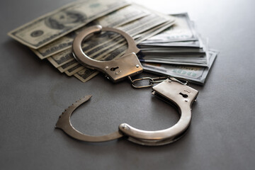 handcuffs and one hundred dollars on the wooden table