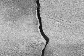 Vertical big crack on old stone wall, abstract image of cleft, background textured. Close-up. Copy space. Black and white photo. Selective focus.