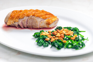 roasted duck breast served with salad of spinach leaves and pine nuts