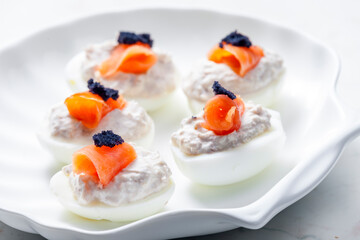 boiled eggs filled with tuna fish spread and smoked salmon and  black caviar on the top