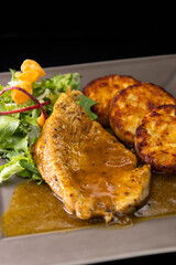 poultry meat with sauce served with hash browns and salad