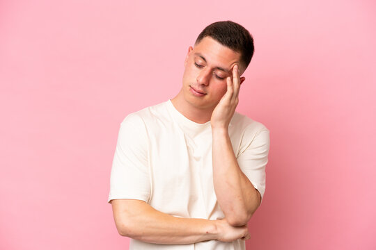 Young Brazilian man isolated on pink background with headache