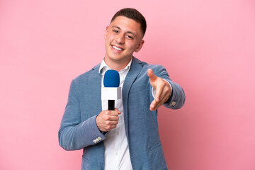 Young brazilian presenter man isolated on pink background shaking hands for closing a good deal