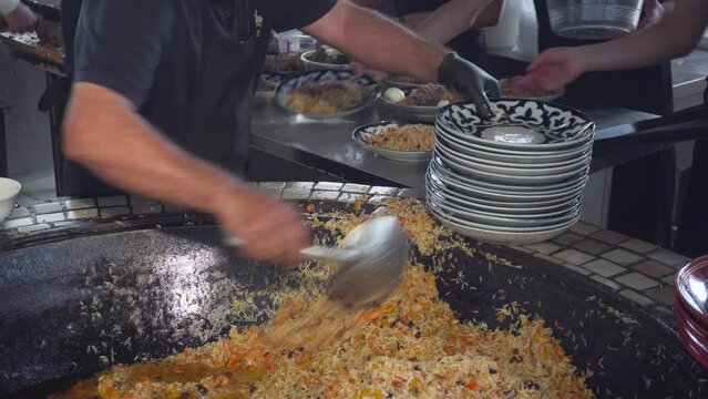 Cookers are putting plov (pilaf) on plates, Tashkent, Uzbekistan