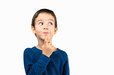 Pensive kid looks away at copy space thinking isolated on a white background, funny kid lips hold...