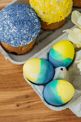 Easter cakes in the colors of the flag of Ukraine, yellow and blue in a cardboard stand with eggs, Easter eggs. place for text. selective focus
