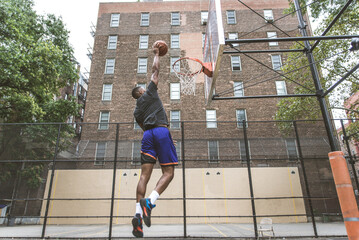 Athletic african american basketball player training on a court in New York - Sportive man playing basket outdoors - obrazy, fototapety, plakaty
