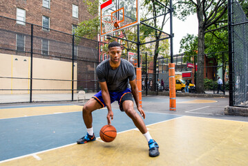 Athletic african american basketball player training on a court in New York - Sportive man playing...