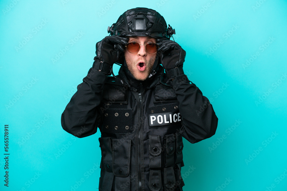 Canvas Prints SWAT caucasian man isolated on blue background with glasses and surprised