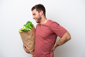 Young caucasian man holding a grocery shopping bag isolated on white background suffering from backache for having made an effort