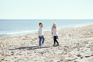 Two toddlers on the beach smiling with mutual understanding
