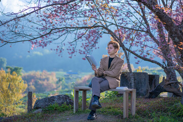 Young men relax and are happy in the fresh beautiful Cherry pink blossom Sakura flowers are in full bloom in the park with a joyful vacation. Concept portrait young fashion loves nature.