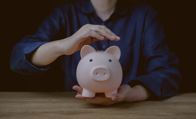 Person Hand holding piggy bank on wood table, saving money wealth and financial concept, Business, finance, investment, Financial planning for retirement. Money growth in success. security money box.