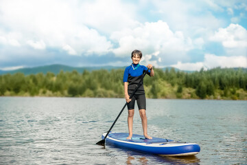 active teen girl paddling a sup board on a river or lake, natural background, active healthy sporty lifestyle