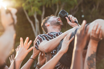 Crowd, surfing and man singing at party, outdoor music festival or social gathering. Microphone,...