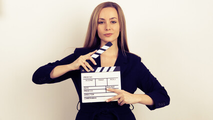 Sensuality beautiful woman with long hair, dressed in black suit in studio, holding clapperboard