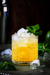 Mai Tai cocktail drink with rum, liqueur, sugar syrup, lime juice, mint and crushed ice. Dark background, bar tools, copy space