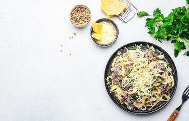 Tagliatelle pasta with mushrooms and parmesan cheese on plate with parsley on grey stone table background, top view. Italian food concept