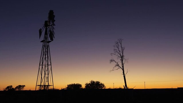 A windmill (windpump) silhouetted against a dawn sky in the Karoo farmlands, south Africa