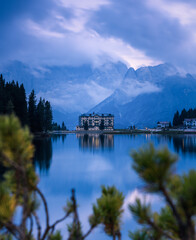 Fototapeta premium See mit Spiegelung und Bergmassiv mit Wolken im Hintergrund.