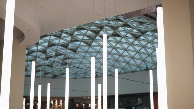 Long light lamps hang from the ceiling illuminating and decorating the room and the surrounding space. Shooting in motion