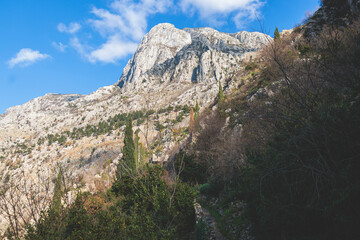 Kotor, Montenegro, process of climbing to the top of San Giovanni Fortress, Fort St. John, old medieval town, hiking on the Ladder of Kotor, sunny day with a blue sky and mount Lovcen and Orjen